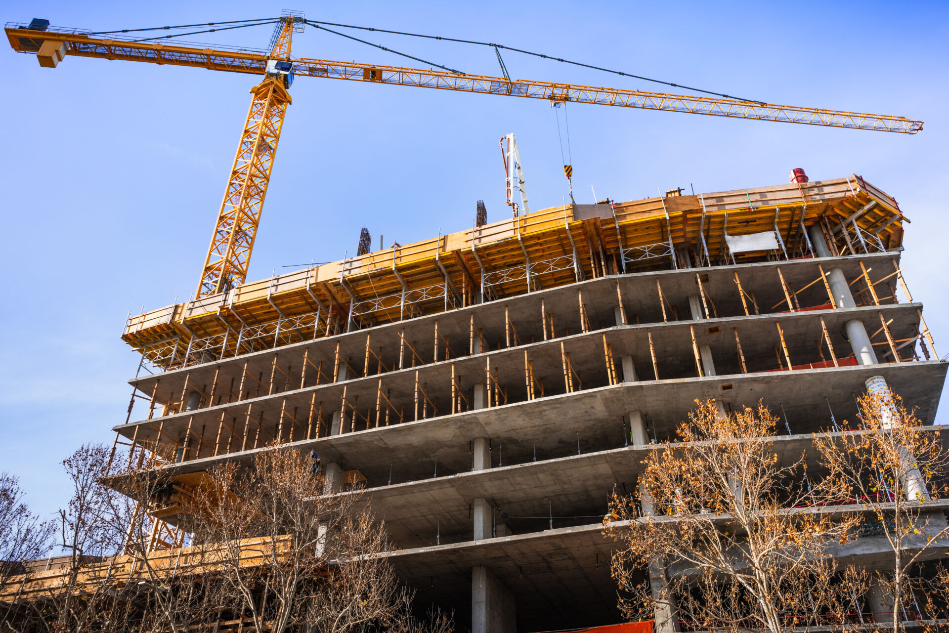 Multi-level concrete building under construction with tower crane; new residential development